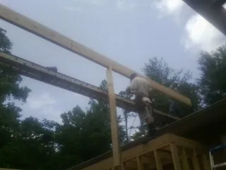 Carpenter setting a ridge beam over a new addition frame — Ice Dam Removal by Roofing Brothers in Bidwell