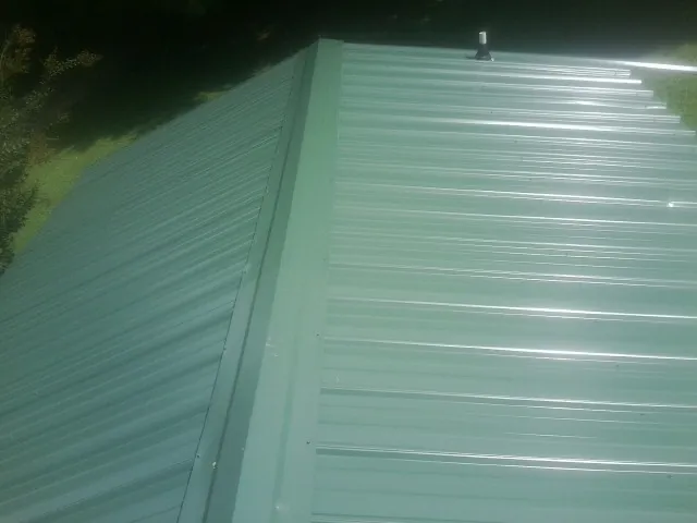 New green metal panels meeting at the ridge of a roof — Flat Roof Repair work by our crew in Bidwell