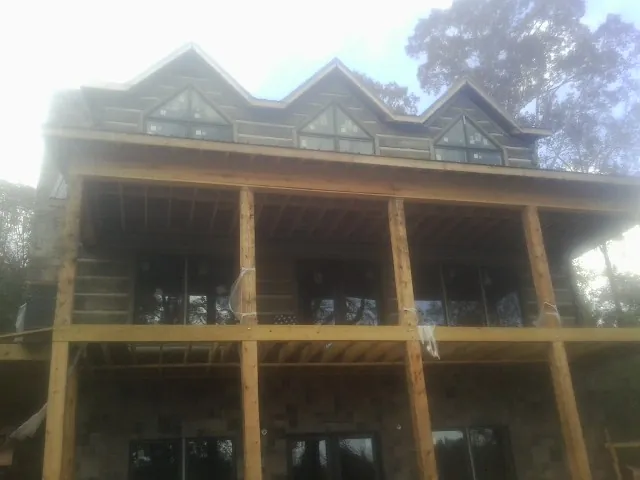 Dormers and porch framing on a large log home under construction — Roof Coating work by our crew in Bidwell