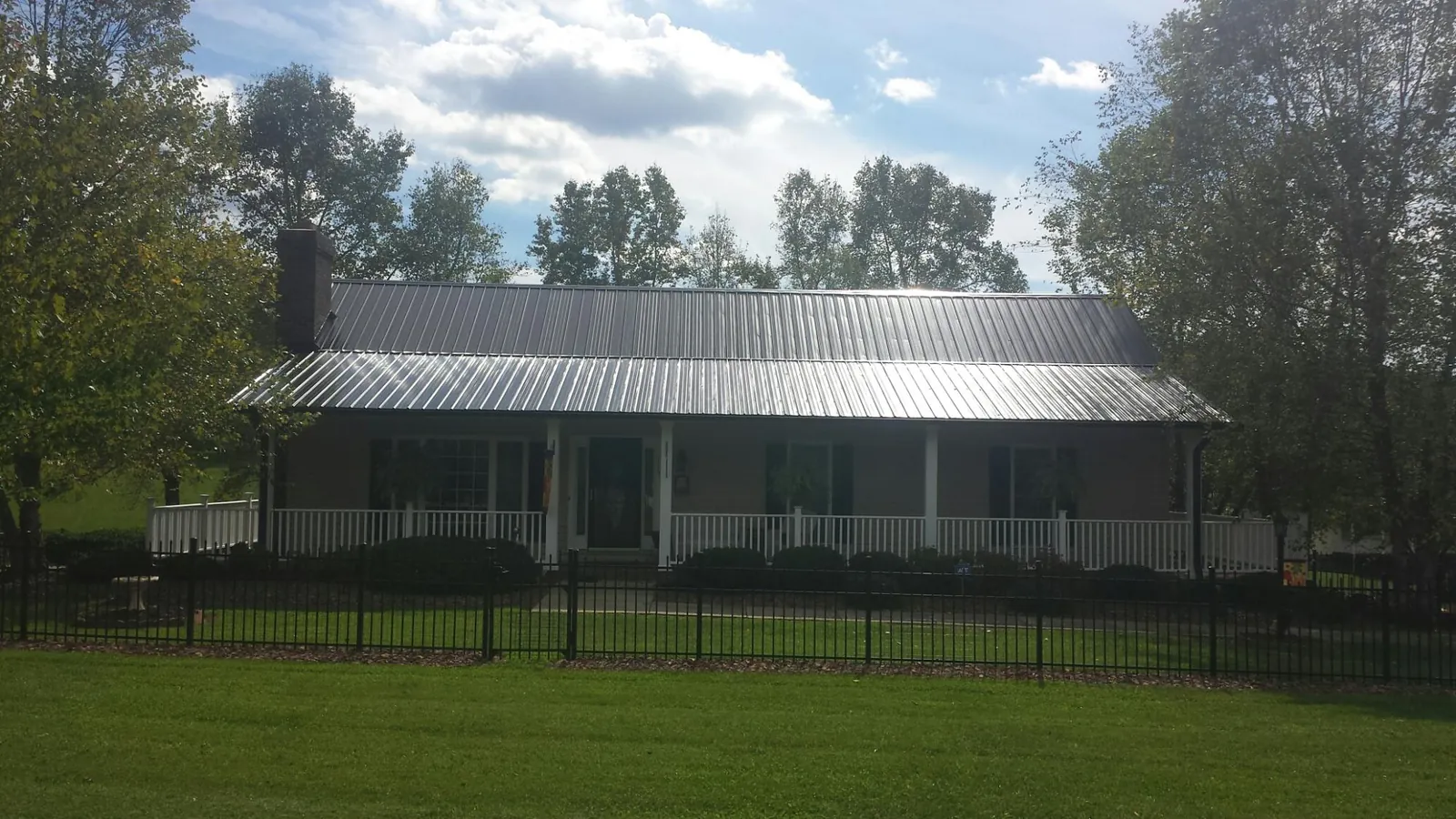 Gray metal roof on a brick ranch with a full width front porch — Gutter Guard Installation work by our crew in Bidwell