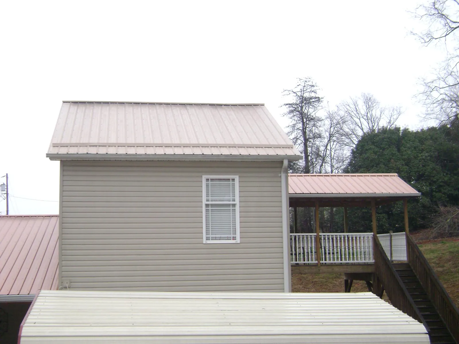 Tan metal roofs on a two story addition and attached porch, from a Roof Replacement job in Bidwell
