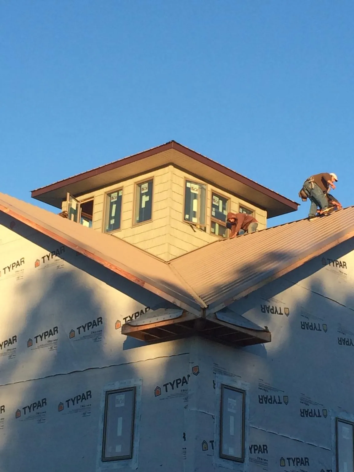 Roofers working around a rooftop cupola on a new metal roof at sunset — Roof Waterproofing in Bidwell by Roofing Brothers